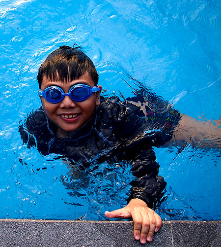 Boy in swimming pool wearing goggles