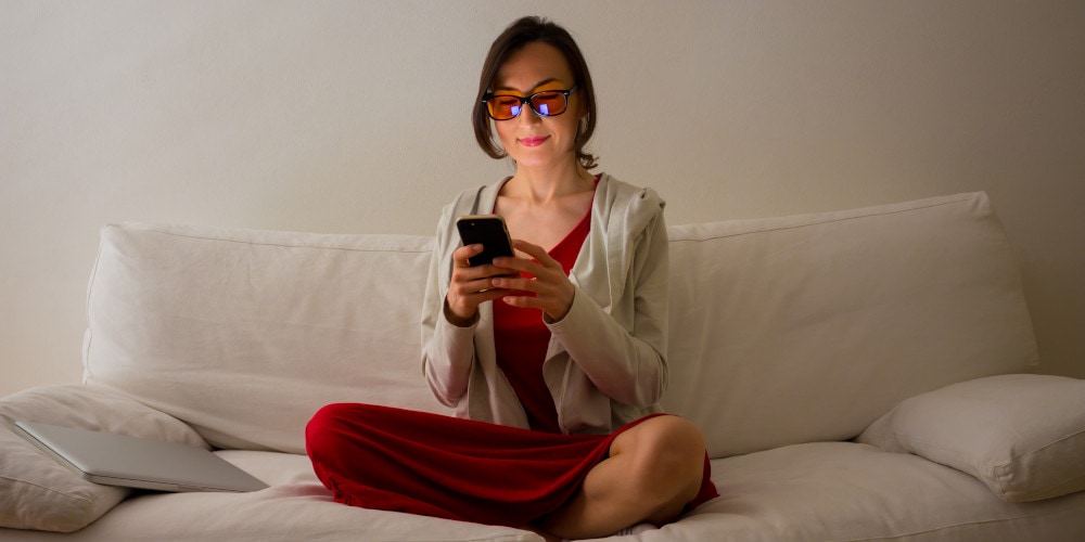 Woman looking at phone while wearing blue light blocker glasses