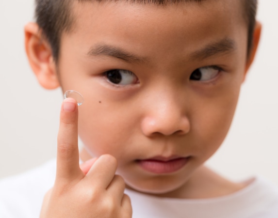 Young boy looking at contact lens