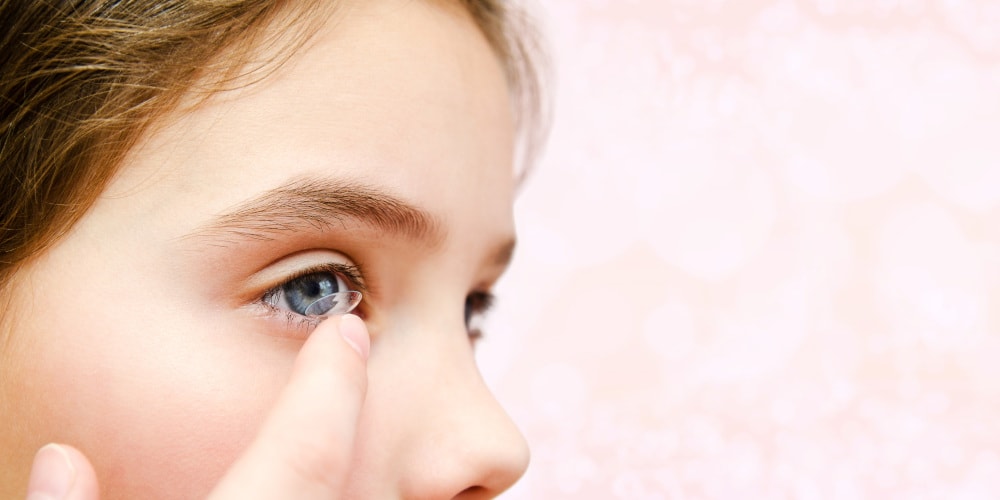 Young girl putting in contact lens