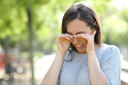 Blurred image of a woman experiencing eye discomfort outdoors, at Assil Gaur Eye Institute, specializing in eye care.