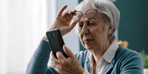 Elderly woman examining her eyes with glasses at Assil Gaur Eye Institute.