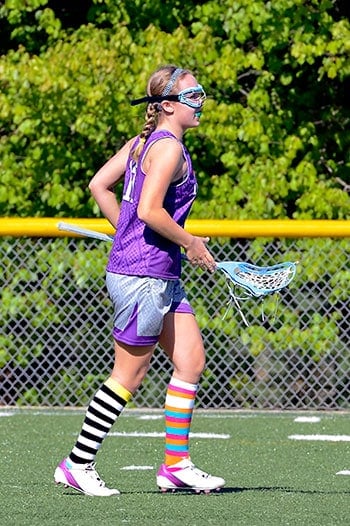Young girl playing lacrosse with eye goggles