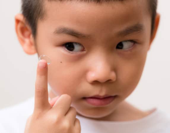 Child applying eye drop, eye health and vision correction services.
