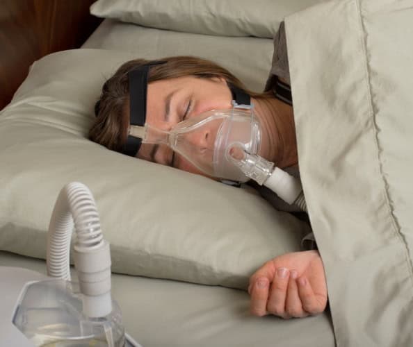 Patient sleeping with oxygen mask for eye-related treatment.