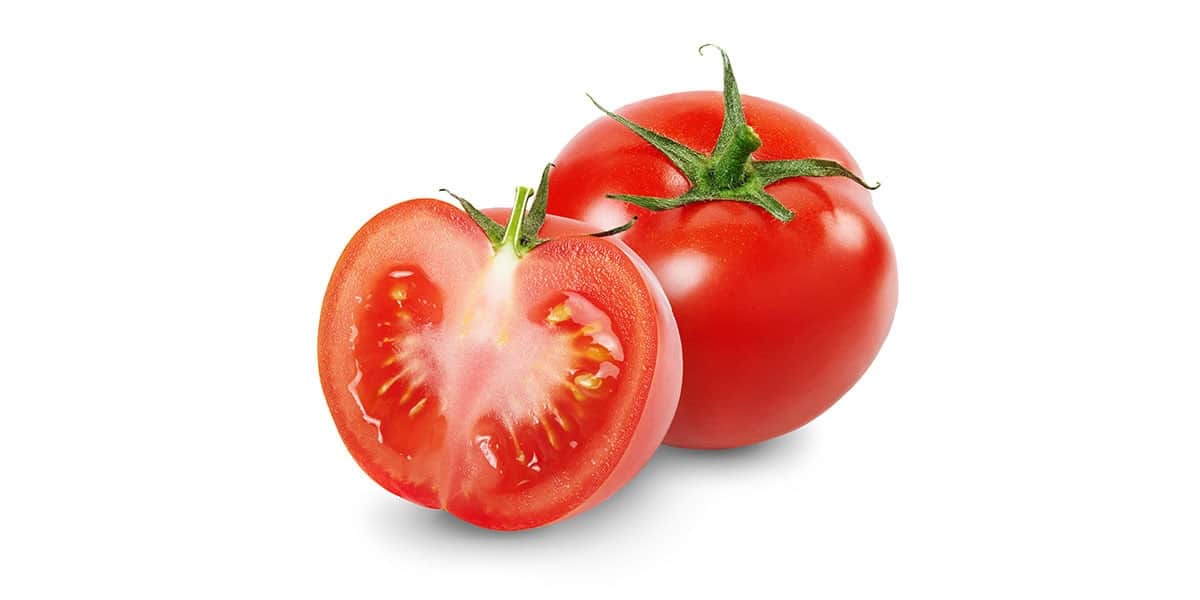Close-up of fresh tomato with one cut in half, highlighting vibrant red color and juicy interior.