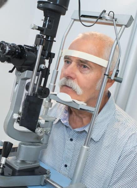 Elderly man undergoing eye examination using specialized slit lamp equipment at Assil Gaur Eye Institute.