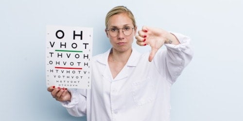 Optometrist holding eye test chart, giving thumbs down at Assil Gaur Eye Institute.