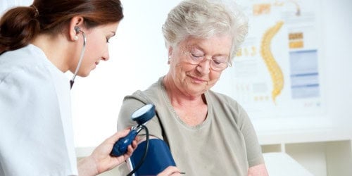 Close-up of elderly woman getting blood pressure check at Assil Gaur Eye Institute, leading ophthalmology center.