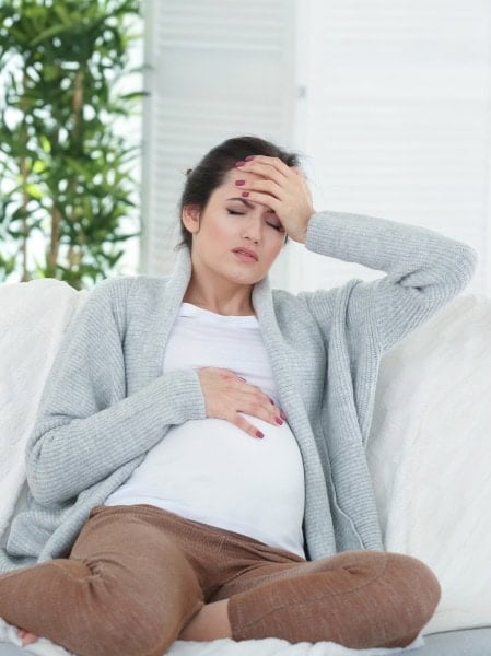 A pregnant woman experiences headache and discomfort, highlighting the importance of expert eye care at Assil Gaur Eye Institute.
