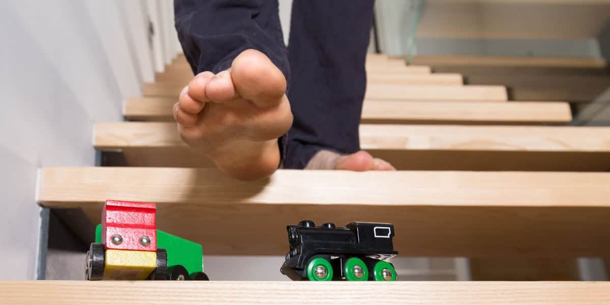 Alt text: Child balancing on wooden planks with track toys, promoting eye coordination and balance.