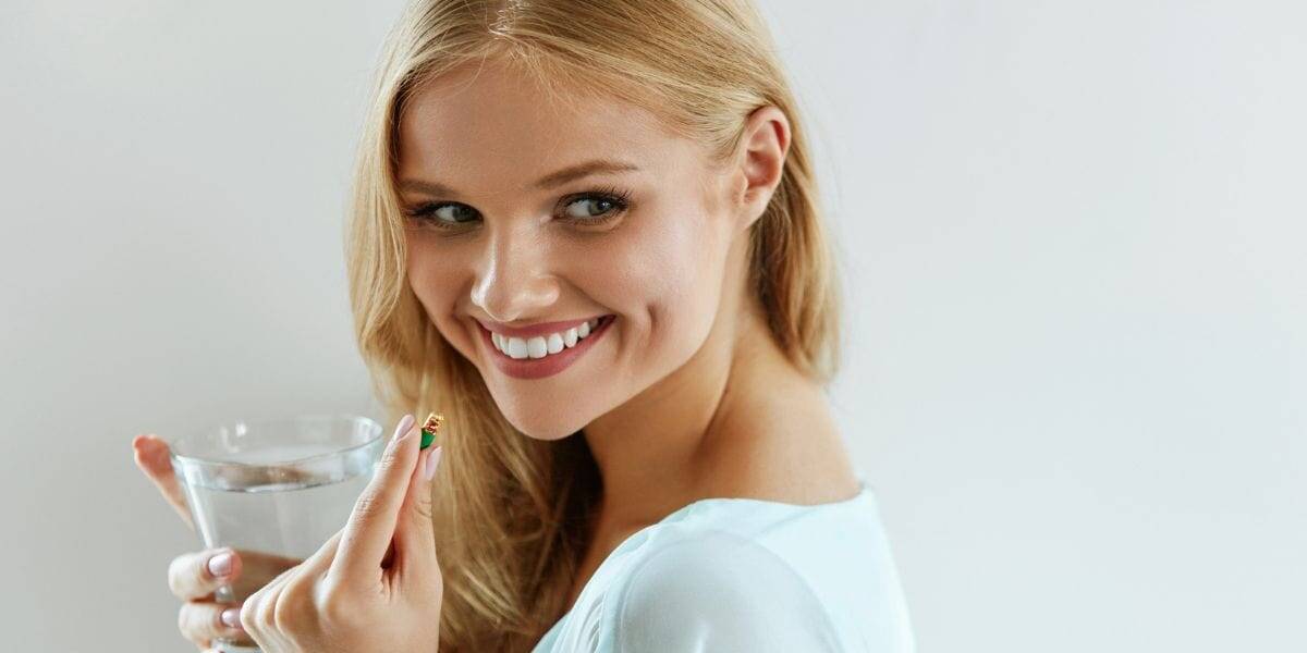 Close-up of smiling woman holding glass of water, promoting health and eye wellness.