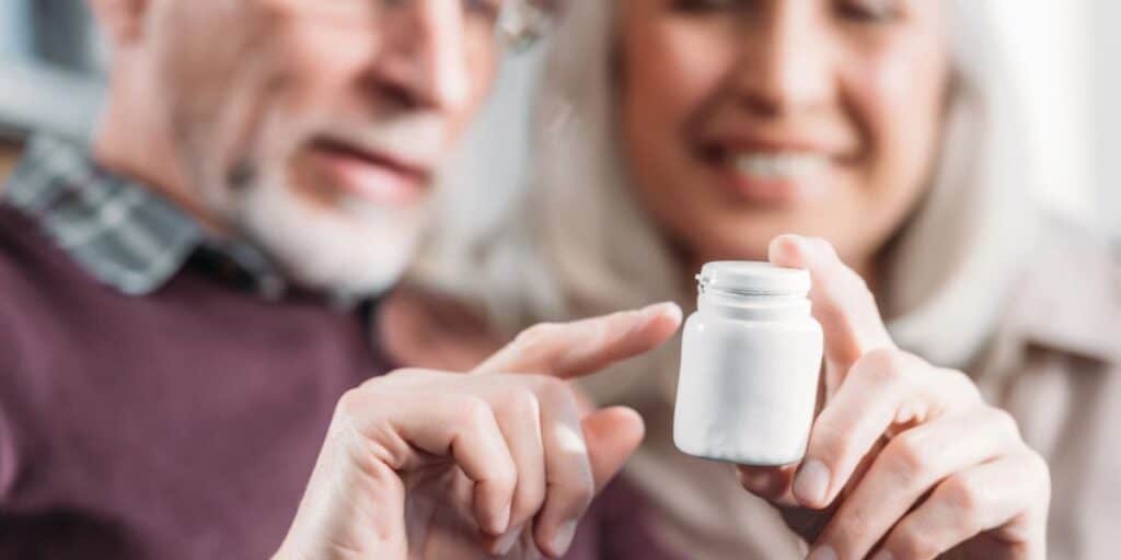 Close-up of elderly man and woman discussing eye health with eye drops container.