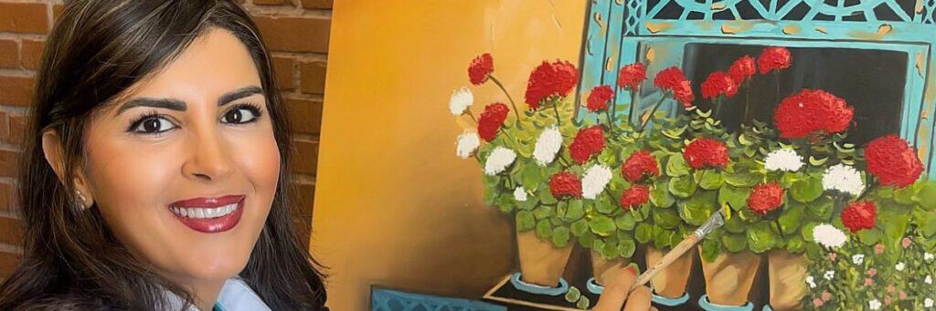 Woman smiling near a colorful flower arrangement at Assil Gaur Eye Institute.