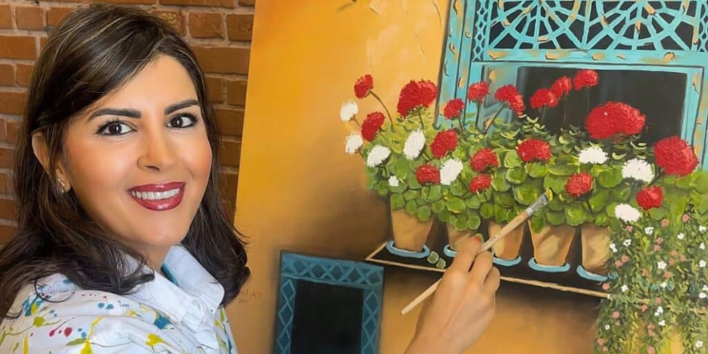 Woman smiling near a colorful flower arrangement at Assil Gaur Eye Institute.