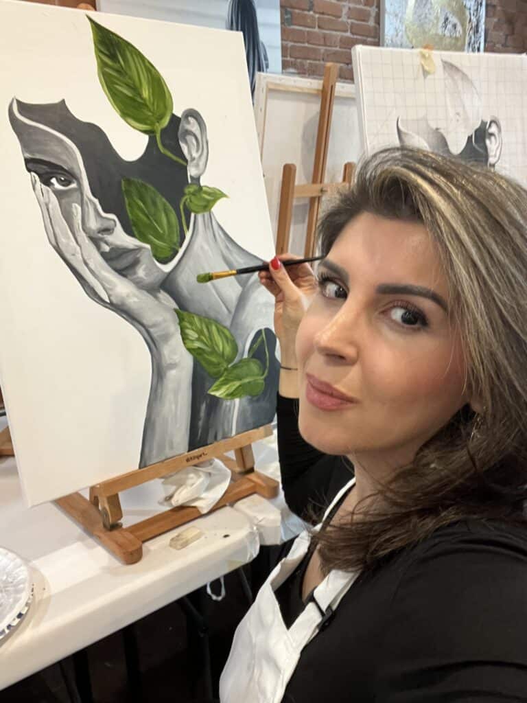 Artist painting a monochrome portrait with green leaves at Assil Gaur Eye Institute.