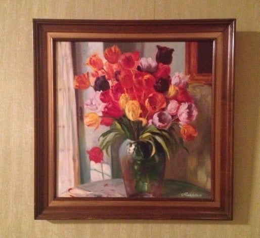 Colorful flower bouquet in a vase, framed and hanging on a wall.