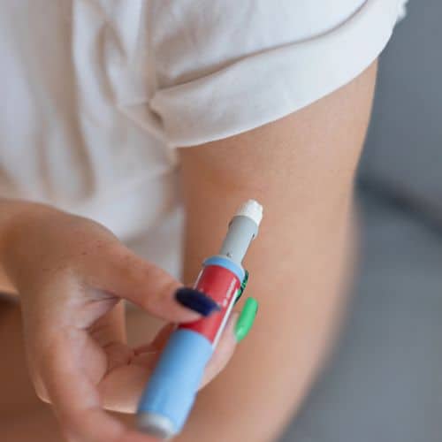Person administering insulin injection into upper arm for diabetes management.