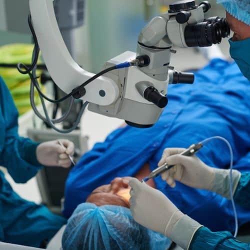 Surgeon performing eye surgery using a microscope at Assil Gaur Eye Institute.